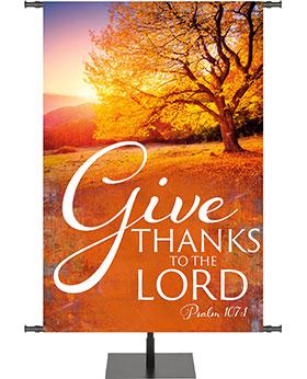 Give Thanks To The Lord Psalm 107:1 Banner for Fall and Thanksgiving with tree covered in Autumn leaves and sunlight shining on hills in the distance